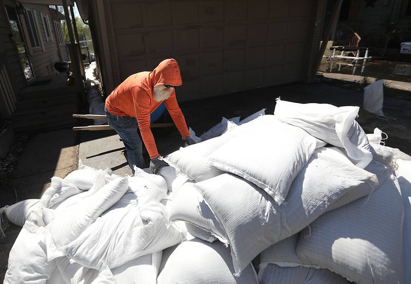 A volunteer loads sandbags into a wheelbarrow as he and  McHenry Home Depot volunteers work to protect a home as flooding continues on the Fox River on Wednesday, April 22, 2026, near Burton’s Bridge.