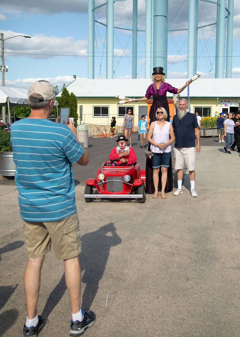 DuPage County Fair attendees pose for a photo with a clown and stilt walker at the DuPage Event Center & Fairgrounds on Saturday, July 30, 2022.