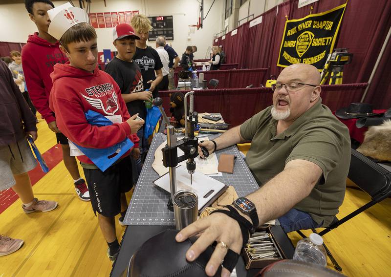 John Simpson of Simpson Leather Crafts shows Fulton eighth-grader Kadin Cossman a handmade product Friday, Oct. 18, 2024, at the Pathways Playground.