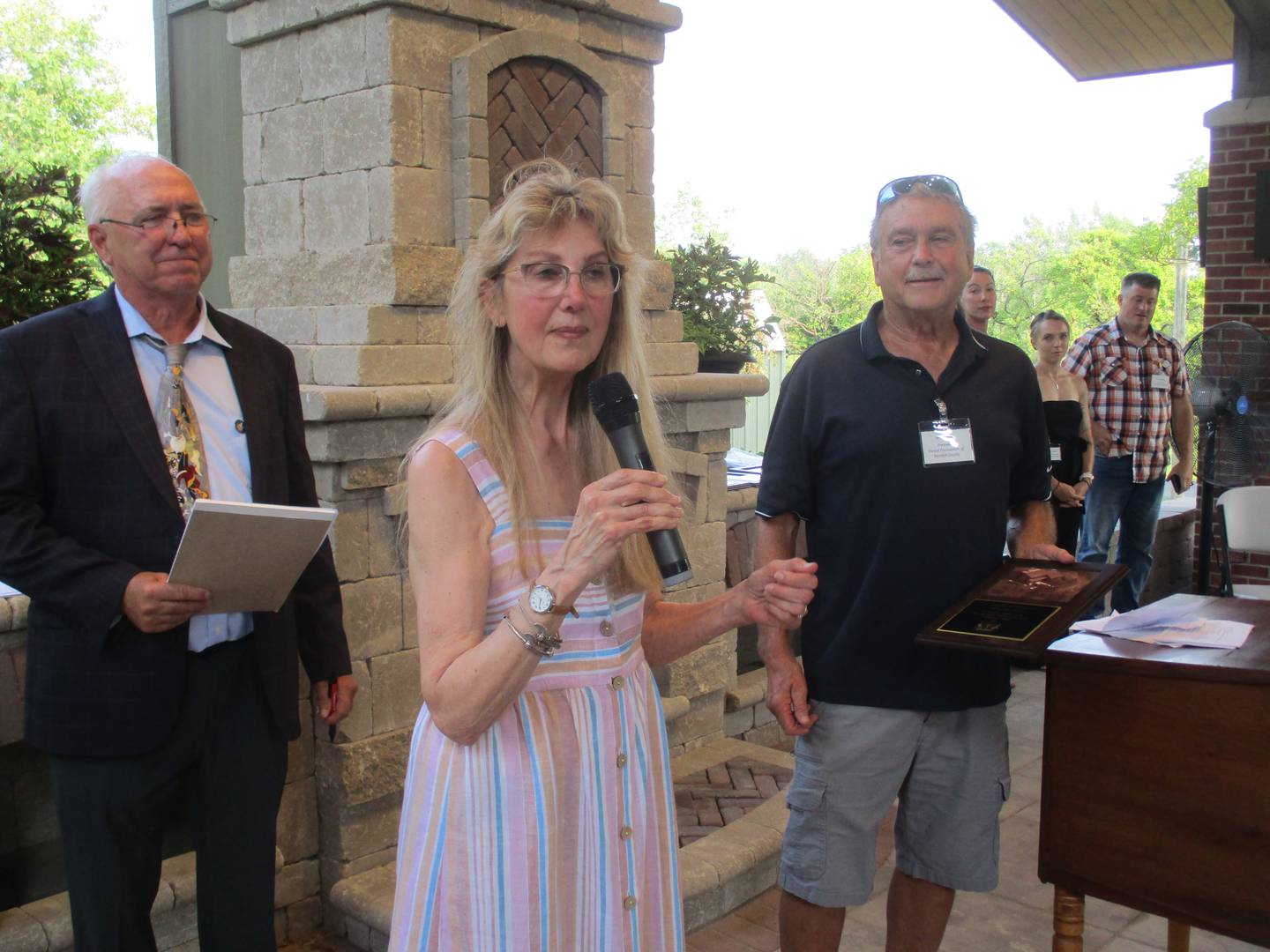 Penelope Pigott Dann was honored during the dedicated for the Pickerill Estate House in the Pickerill-Pigott Forest Preserve on July 15, 2023. At left is Kendall County Forest Preserve District President Brian DeBolt and to the right is Forest Foundation of Kendall County President Jeff Wehrli.