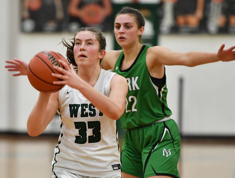 Glenbard West's Makenna Yeager (33) takes aim at the basket as York's Stella Kohl defends during a game on Jan. 22, 2024 at Glenbard West High School in Glen Ellyn.