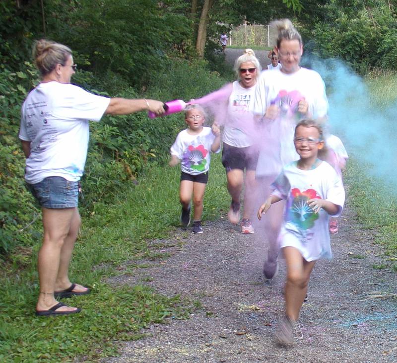 Runners close their eyes as they cross the finish line and get doused with color Saturday, Aug. 6, 2022, during the inaugural Safe Journeys Color Run at Twister Hill Park in Streator.