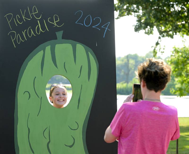 Taryn Biemolt has her photo taken as a giant pickle by Brooke Freeman during Inaugural Pickle Paradise event at Pottawatomie Park in St. Charles on Friday, June 21, 2024.
