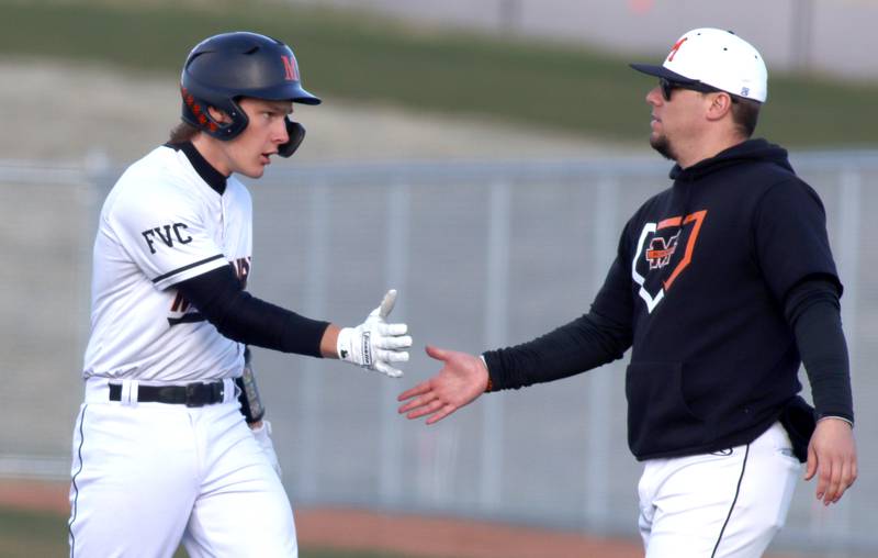 McHenry’s Kamrin Borck is greeted at first base after knocking a single against Huntley in varsity baseball at McHenry Friday night.