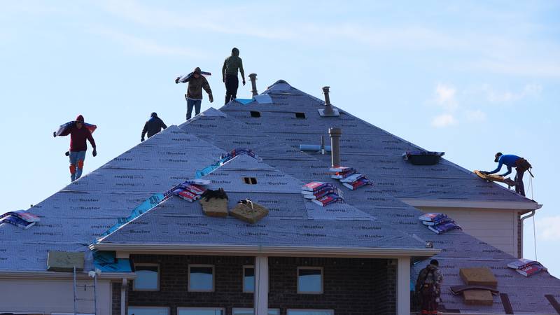 Roofers work atop a house in Anna, Texas, Thursday, Dec. 18, 2025. (AP Photo/LM Otero)