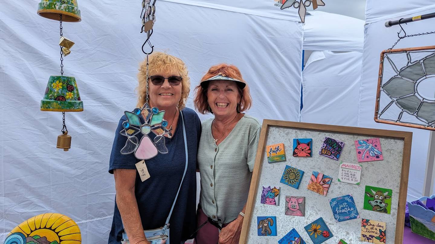 Diane James of Sandwich (left) and Kat Apostle of Braceville (right) of the Flying Purple Pigs said plenty of people were looking at their handcrafted stained glass art, hand-painted stones, terra cotta wind chimes and small canvas magnets on Saturday, June 8, 2024, at Old Canal Days in Lockport.