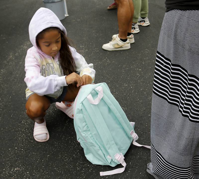 Tudy Villalobos, 8, opens her new backpack during a Woodstock School District 200 Back to School Coming to You event at Northwood Middle School on Tuesday, Aug. 6, 2024. The location was one of twelve stops on the tour that gave out backpacks and school supplies, provided registration help and computer repair.