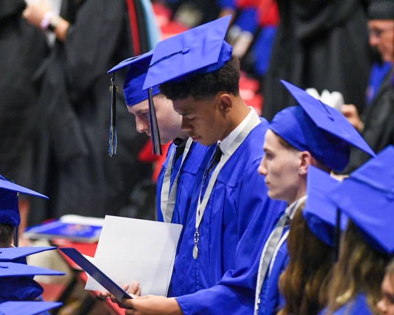 A St. Charles North graduate looks at his diploma after returning to his seat during the graduation ceremony on Monday, May 18, 2026, held at the Convocation Center in DeKalb.