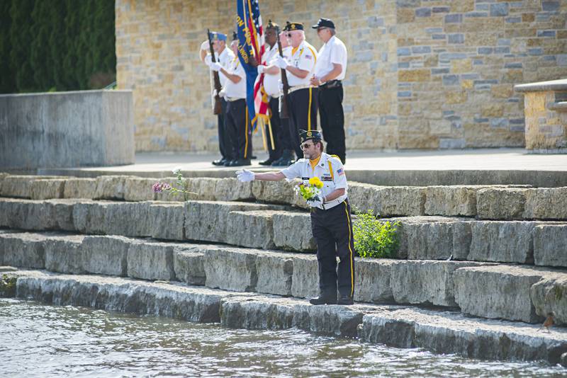 Dave Devine lays flowers in the Rock River Monday, May 30, 2022 at the Dixon riverfront to honor the sailors who died at sea.