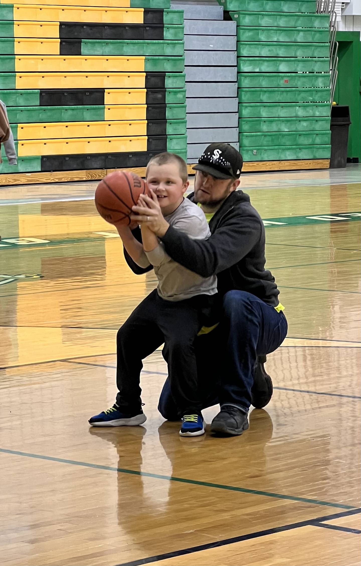 Alan Maziur, 7, and son of Jenna Maziur, a girls basketball coach at Providence Catholic High School in New Lenox, receives a little basketball guidance from his father Al Maziur. Alan has nonverbal autism and loves basketball. He will participate in a basketball camp for students with special needs in January 2023. Jenna will help run it.