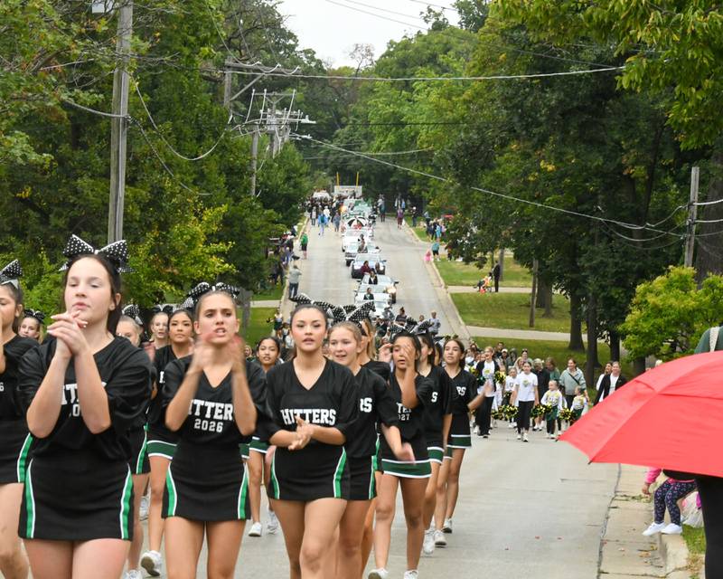 Glenbard West cheerleaders preform cheers along the homecoming parade route on Saturday Sept. 28, 2024, as the homecoming court and floats follows as rain drizzles during the parade in Glen Ellyn.