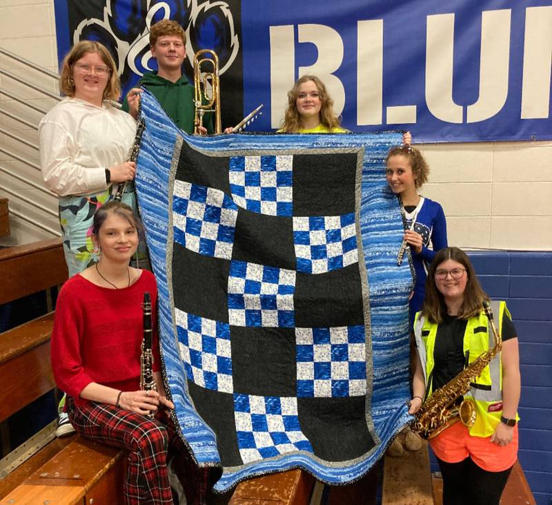 The 2023 senior band members proudly display the quilt following a recent Pep Band performance. Senior members pictured are from bottom left to bottom right: Katelyn Stanfield, Kailey Patterson, Jayden Eggers, Emma Frost, Sadie Thornton, and Bella Whitfield. Absent from the photo was Karter Patterson.
