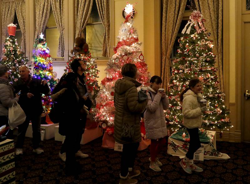 People look at the decorated Christmas trees during the Christmas Tree Walk inside the Opera House during the Lighting of the Square Friday, Nov. 24, 2023, in Woodstock. The annual holiday season event featured brass music, caroling, free doughnuts and cider, food trucks, festive selfie stations and shopping.