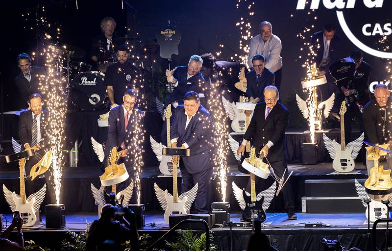 Illinois Gov. JB Pritzker (center), Rockford Mayor Tom McNamara (left) and Hard Rock International COO Jon Lucas smash guitars Thursday, Aug. 29, 2024, during the official opening of the Hard Rock Casino Rockford.