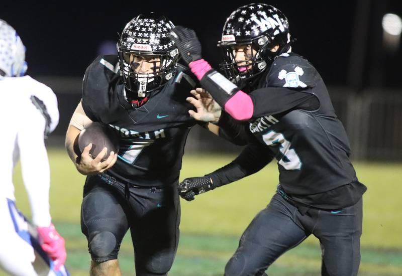 Woodstock North’s Parker Halihan, left, runs the ball as Braeden Berner prepares to block in varsity football at Woodstock North High School on Friday, October 24, 2025.