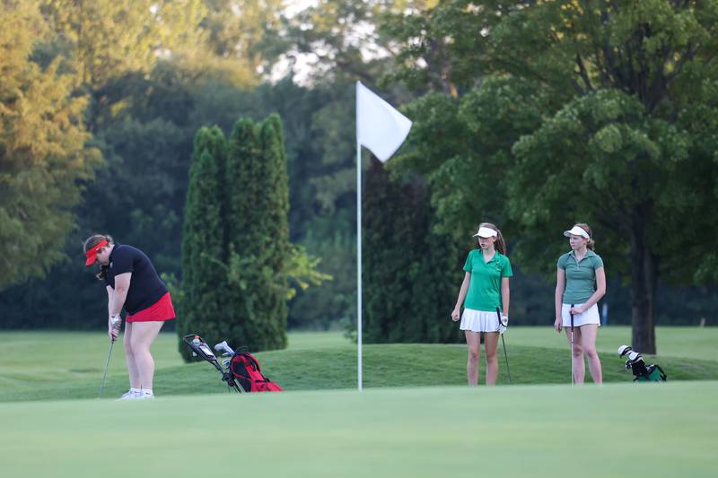 Bradley-Bourbonnais' Emerson Whittington, left, putts as Bishop McNamara's Maggie Manes, center, and Olivia Ouwenga look on during the Boilermakers' 219-235 victory over the Fightin' Irish in the All-City matchup at the Kankakee Elks Country Club on Thursday, Aug. 28, 2025.