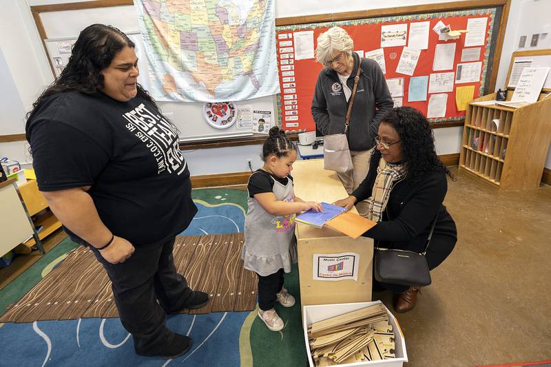 Connie Marney, District Director for Tony McCombie, receives a book from a student in Elizabeth Garcia’s (left) class at Head Start in Sterling.