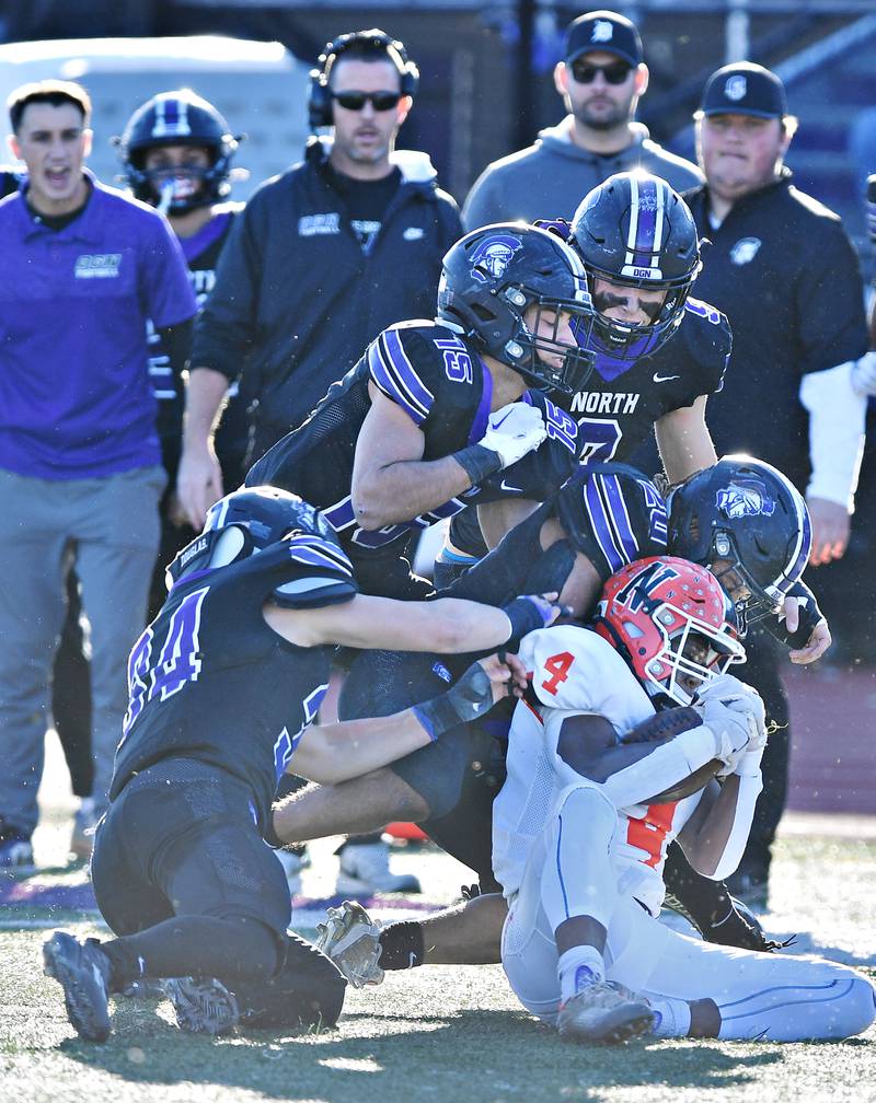Normal Community's Tommy Davis (4) is gang tackled by four Downers Grove North defenders during an IHSA Class 7A semifinal game on Nov. 18, 2023 at Downers Grove North High School in Downers Grove .