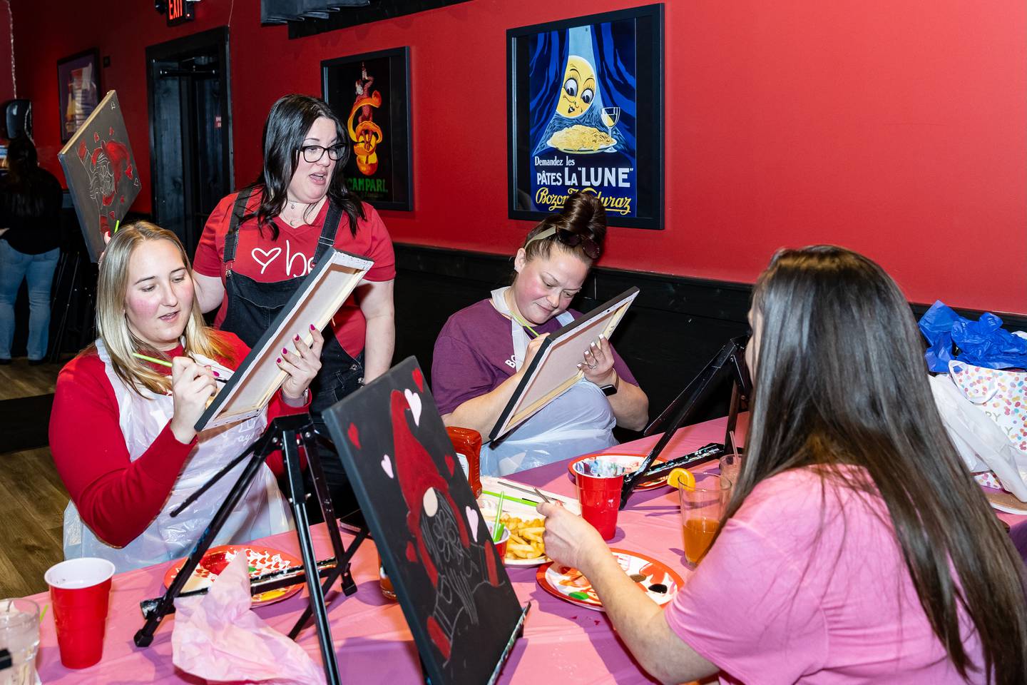 Divine Design Paint Studio owner and artist, Annie Flint, gives tips to Danielle Overbey (Lockport), Britney Roman (Crestwood), and Jenna Mackey (Lockport) during the paint party at Papa Joe's in Lockport on Feb. 6, 2025.