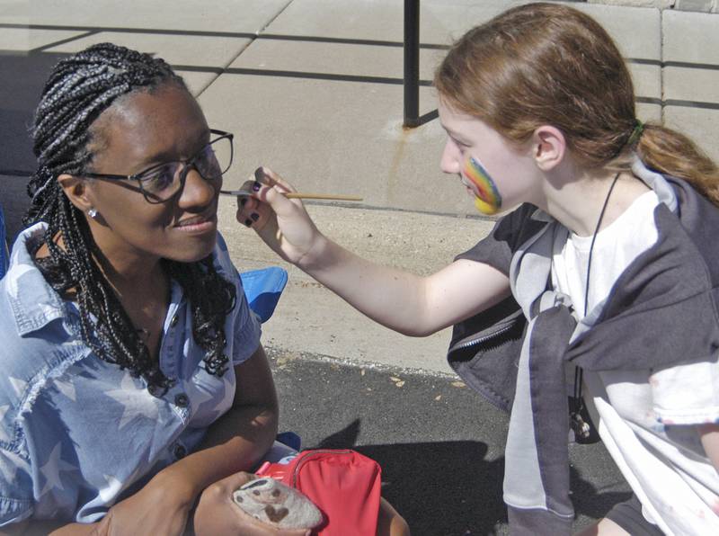 Dana Carmen Weaver, pastor of the 1st Baptist Church in Erie, has her face painted by Reese Anderson at the Port Byron-hosted Great River Tug Fest across the Mississippi on Saturday, Aug. 10, 2024.