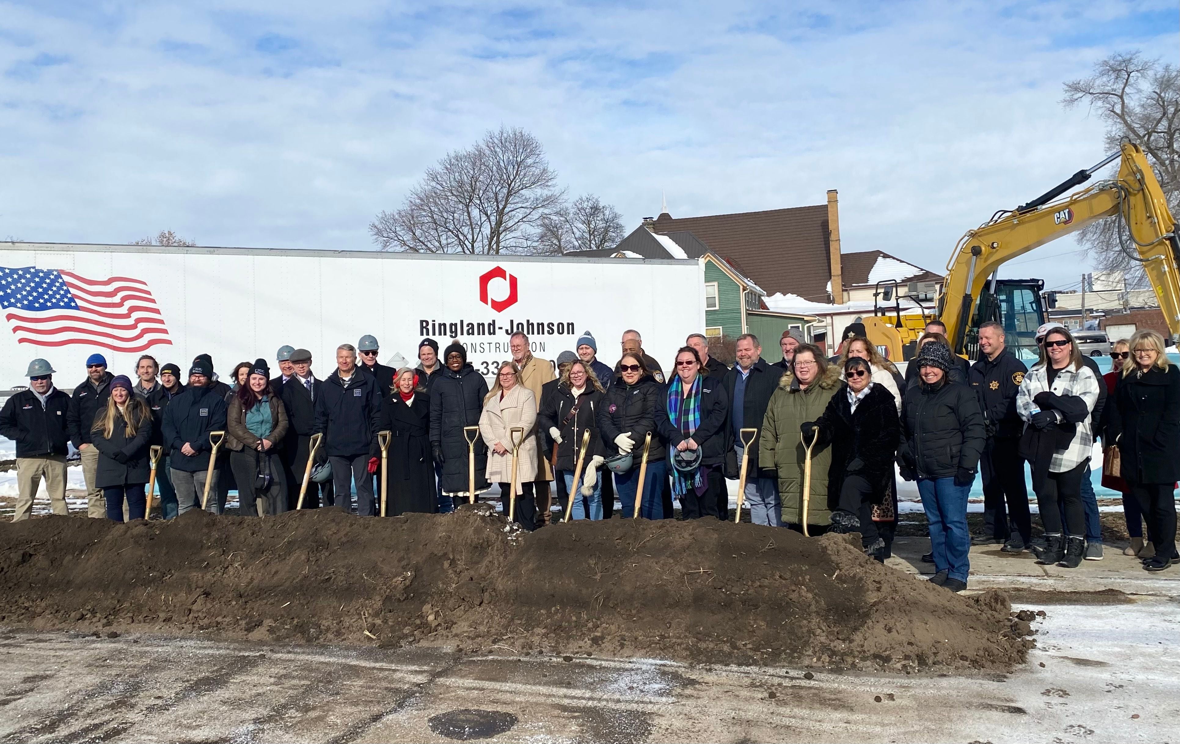 DeKalb area officials including elected leaders, staff and supporters of Safe Passage Inc., pose for a group photo on Friday, Dec. 5, 2025, at the agency's ceremonial groundbreaking to mark the start of construction on a new domestic violence survivor shelter at 217 Franklin St., in DeKalb.