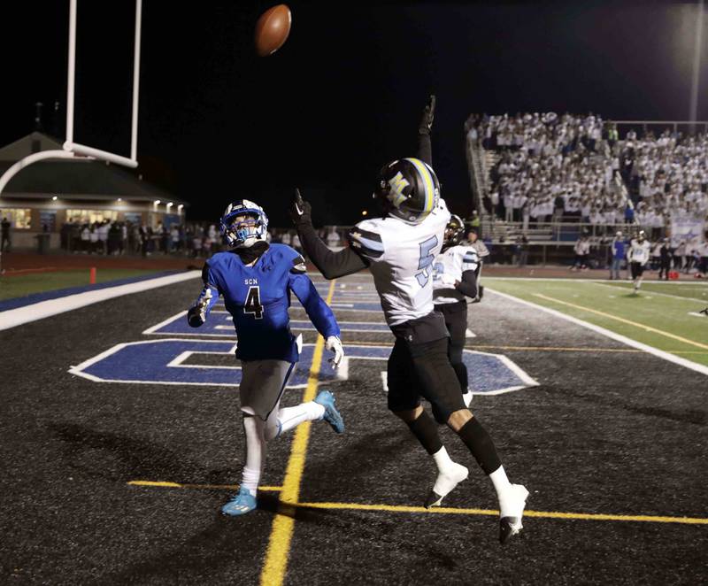 St. Charles North's Jake Mettetal (4) tires to reel in a failed touchdown attempt as Maine West’s Adam Aboebied (5) pressures him Friday October 28, 2022 in St. Charles.