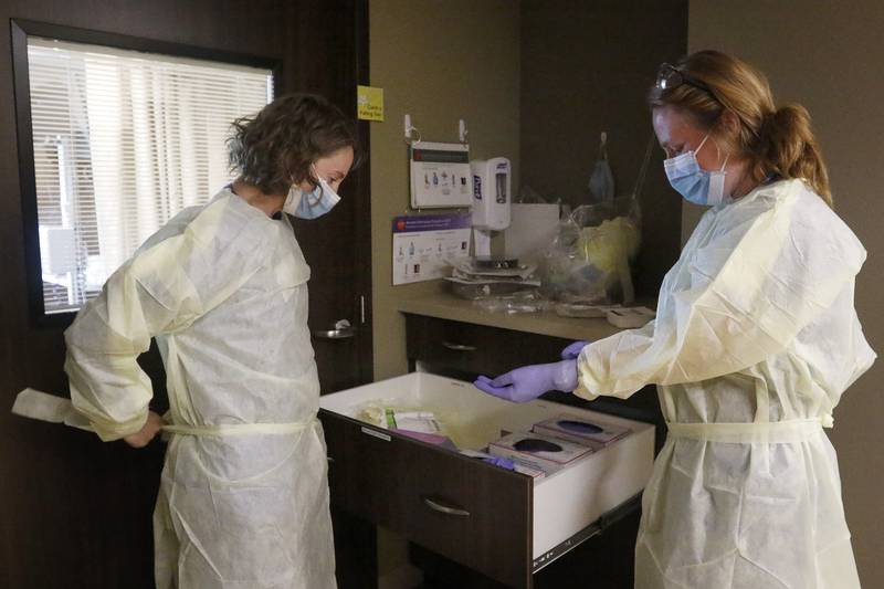 Registered nurses Carolyn Doetsch, left, and Justine Heggem put on personal protective equipment prior to entering a patient's room at Northwest Medicine Huntley Hospital on Wednesday, June 23, 2021, in Huntley.