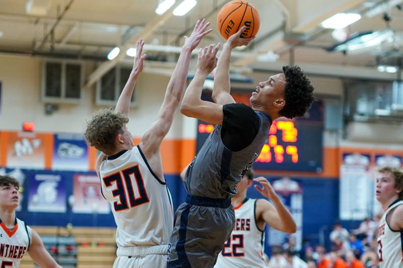 Oswego East's Myles Buchanan (4) shoots the ball in the paint against Oswego’s Brayden Borrowman (30) during a basketball game at Oswego High School on Tuesday, February 18, 2025.