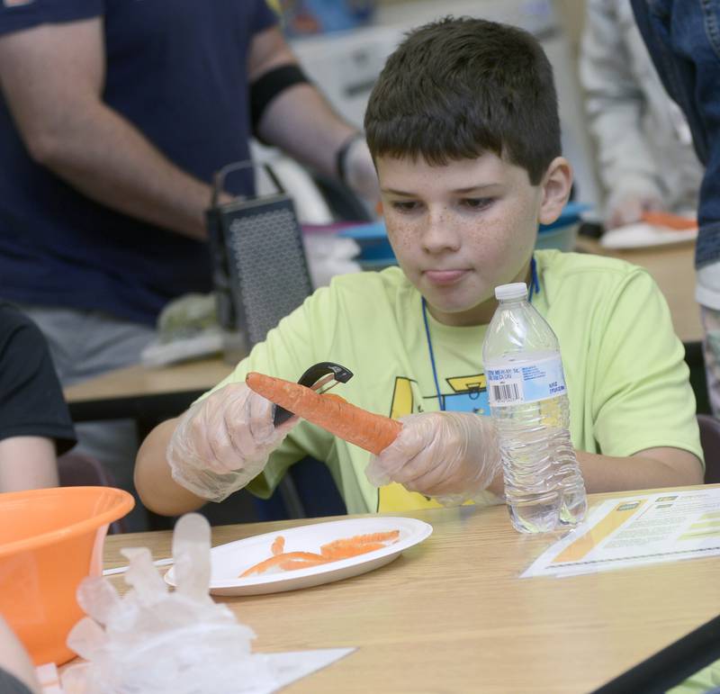 Alex Cooper grates a carrot Wednesday at Northlawn Junior High in Streator during the Illinois Junior Chefs program. the class was preparing to make Veggie Chow Mein.