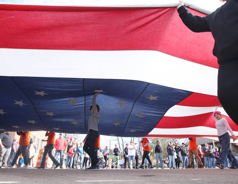 Volunteers carry a large American Flag down Mill Street during the 16th annual Utica Veterans Parade and Air Show on Sunday Nov. 5, 2023 downtown Utica.