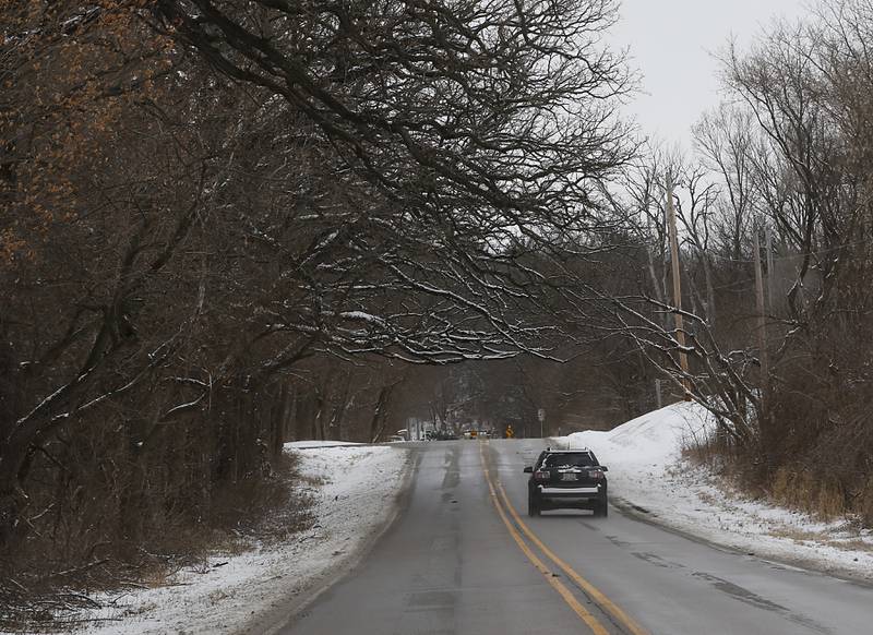 A car travels under some snow covered branches along Mason Hill Road in Bull Valley Wednesday, Feb. 2, 2022, after the northern part of McHenry County missed the brunt of a winter storm that dumped up to 8 inches of snow in Joliet.