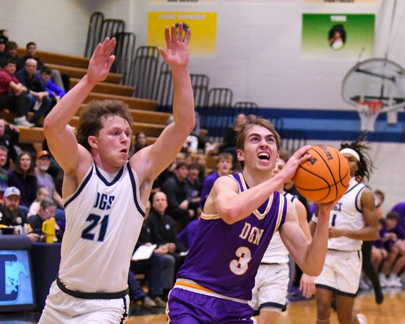 Downers Grove North's Nolan Hurter (3) makes a basket while being fouled by Downers Grove South's Daniel Laurich (21) during the game on Saturday Dec. 21, 2024, held at Downers Grove South High School.