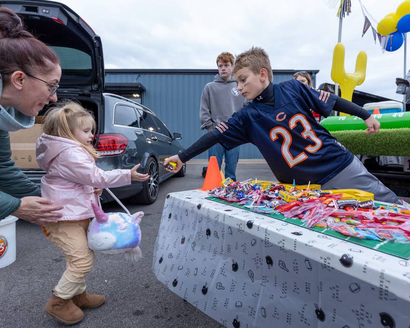 Sky Lane gets handed candy by Trenton Edwards at the trunk or treat event on Saturday, October 25, 2025 at Illinois Valley Auto Group in Peru.