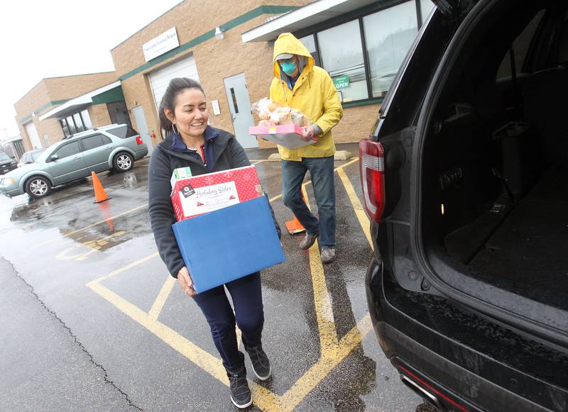 Sandra Wieting, of Grayslake, and Vic Ligenza put boxes of food in the back of a car for a patron Jan. 16 at the PLAN Food Pantry in Round Lake Beach.