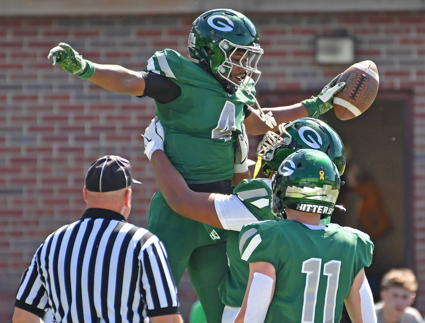 Glenbard West’s Jamarcus Kelly (4)  is lifted by teammate Josiah Wallace after scoring a touchdown against Lyons Township during a game on September 27, 2025 at Glenbard West High School in Glen Ellyn.