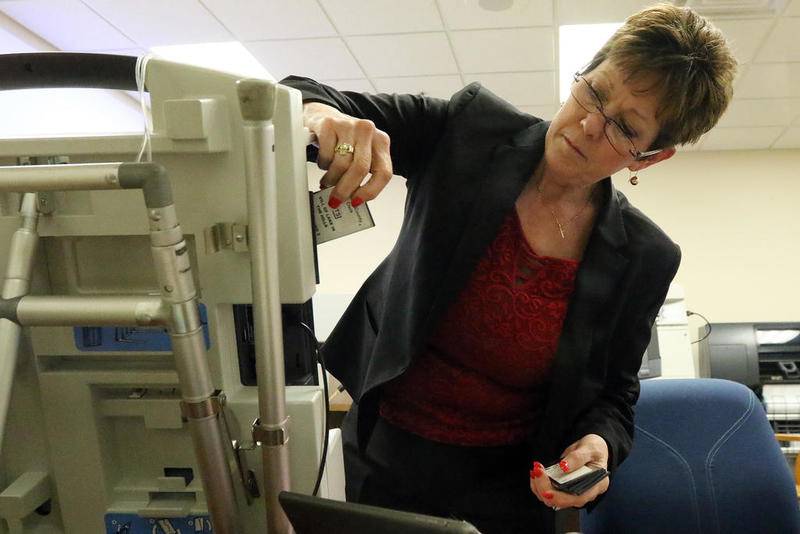 McHenry County Clerk Mary McClellan inserts a memory card to tabulate votes at the McHenry County Administration Building on Tuesday, March 20, 2018, in Woodstock.