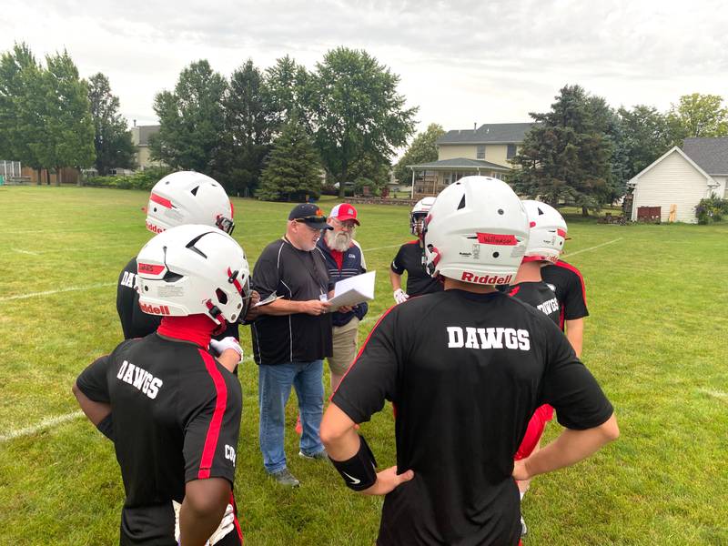 New Streator coach Matt Cloe, center with playbook in hand, talks things over with his Bulldogs between plays at a July 9, 2024, 7-on-7 at Dwight.