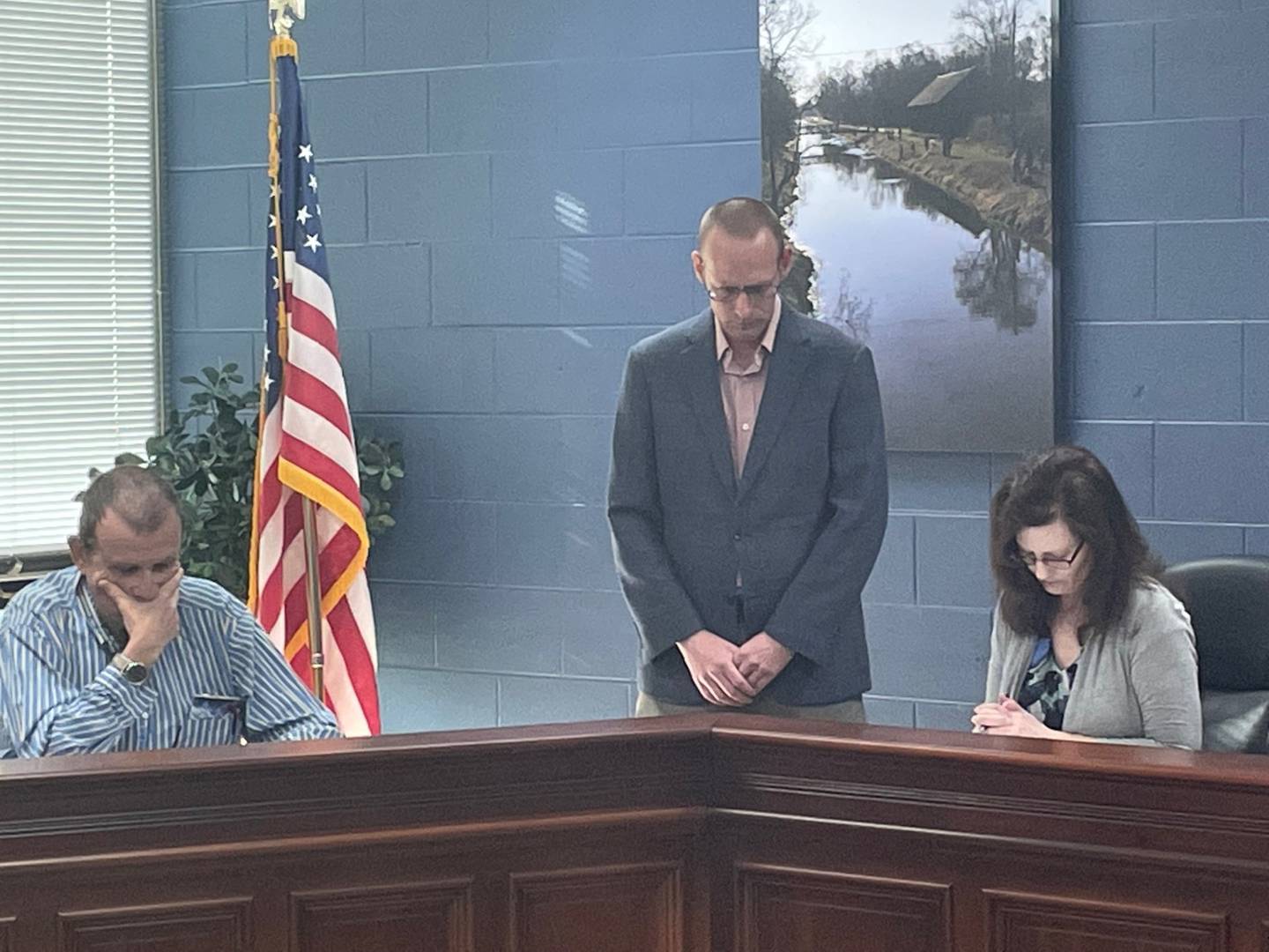Utica Mayor David Stewart (standing) leads a moment of silence for the late Mary Pawlak on Thursday, May 25, 2023, while Planning Commissioner Mike Brown and Village Clerk Laurie Gbur bow their heads. Pawlak, a longtime village trustee and election judge, died Tuesday on her 77th birthday.