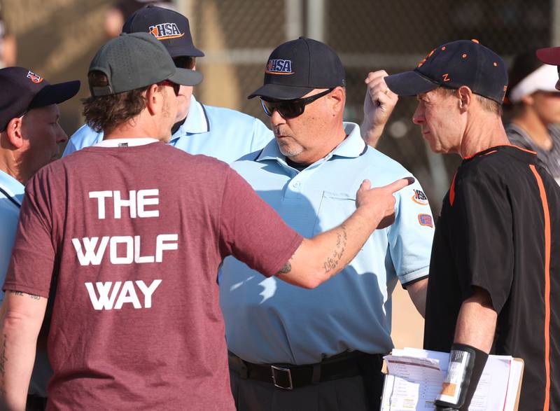 Prairie Ridge head coach Scott Busam (left) and Crystal Lake Central head coach Brian Strombom talk to the umpires after controversial collision on the base paths in the sixth inning Friday, June 6, 2025, during their Class 3A sectional final game at Sycamore High School.
