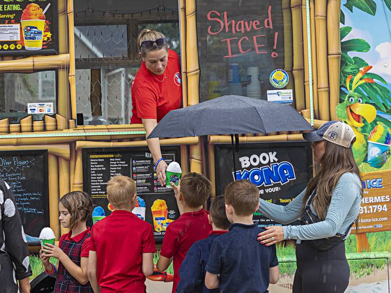 Emily Hermes hands down shaved ice from her Kona Ice truck Friday, Sept. 22, 2023 outside of St. Mary’s School in Dixon. The students were treated to the icy delight for their participation in the “Walk, Pray, Love-a-Thon” event.