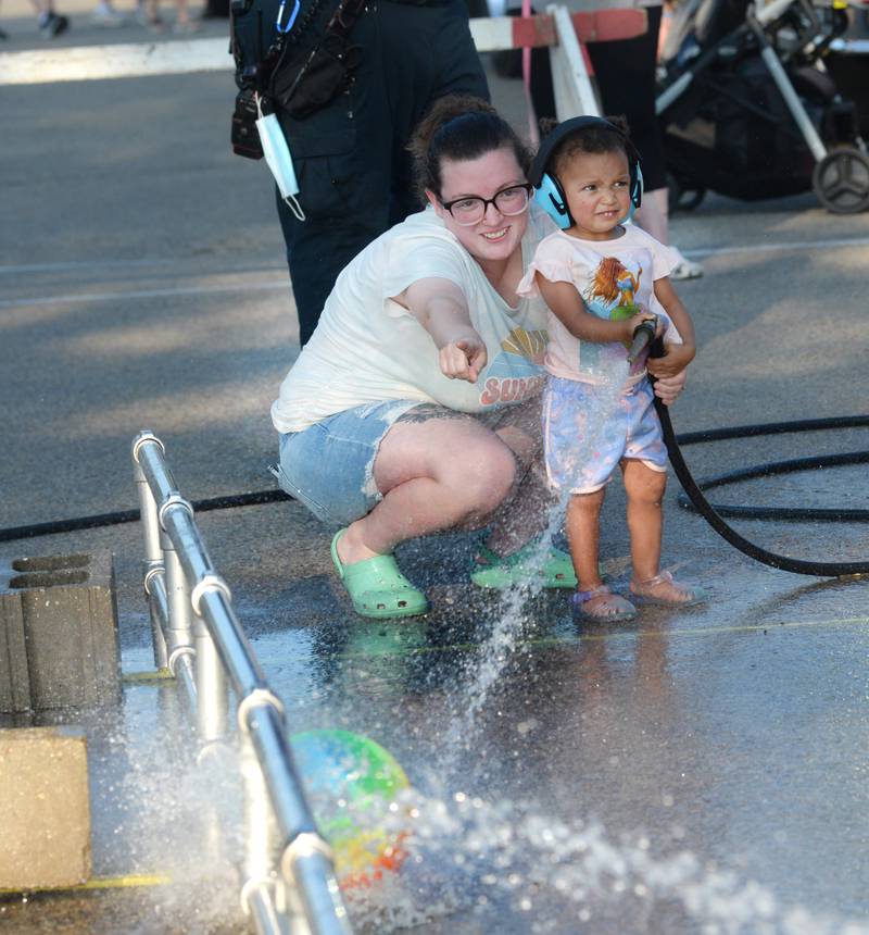 Shayeny Ritt tries to give some pointers to Zuri, 2, of Mt, Morris as they take part in the kids' water fight at Let Freedom Ring on Monday. The event was organized by the Mt. Morris Fire Department.