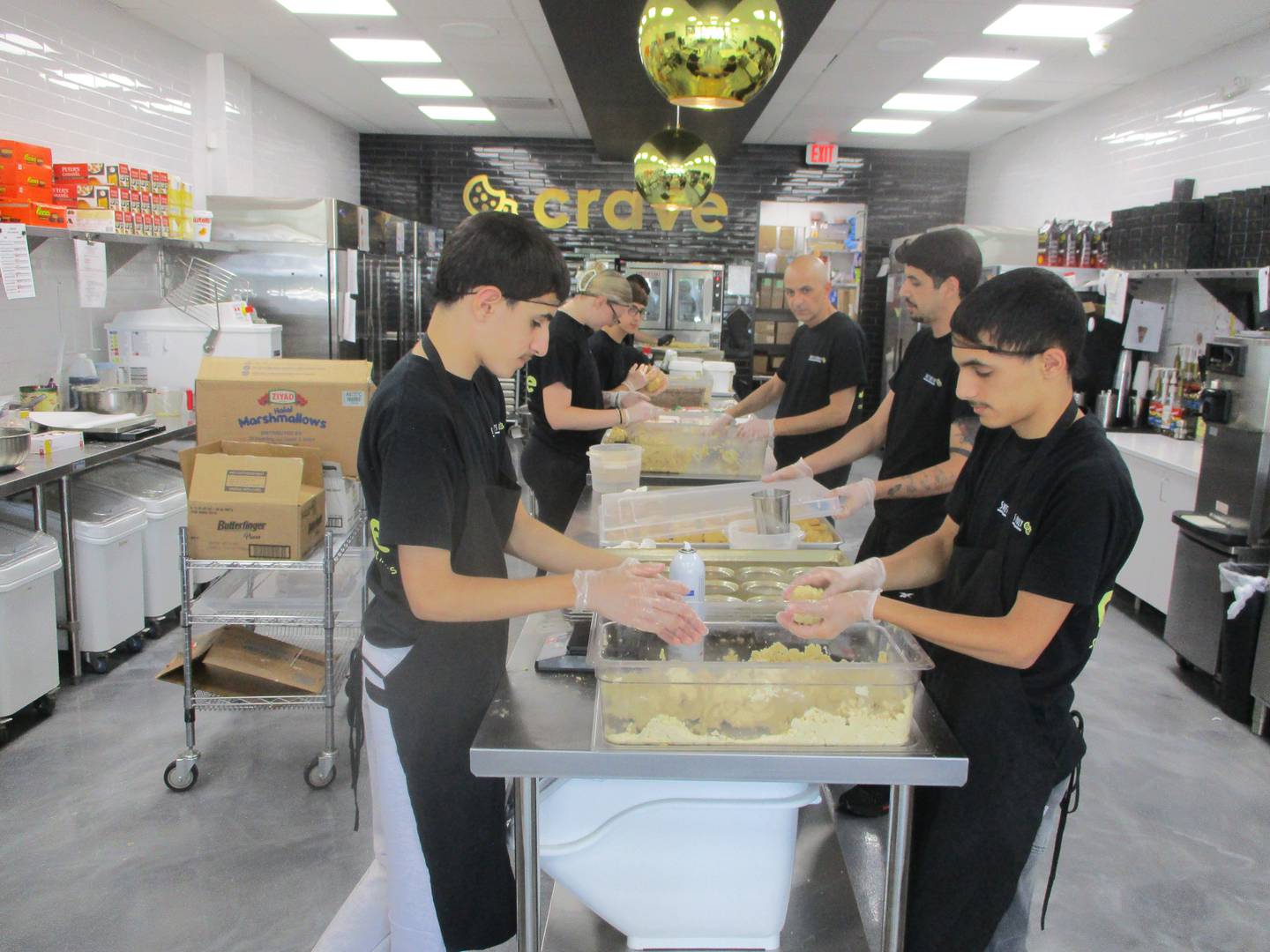 Workers at Crave Cookies prepare cookies for a day of business on Wednesday at the Joliet store that opened in January in the business district surrounding the Louis Joliet Mall. June 11, 2025