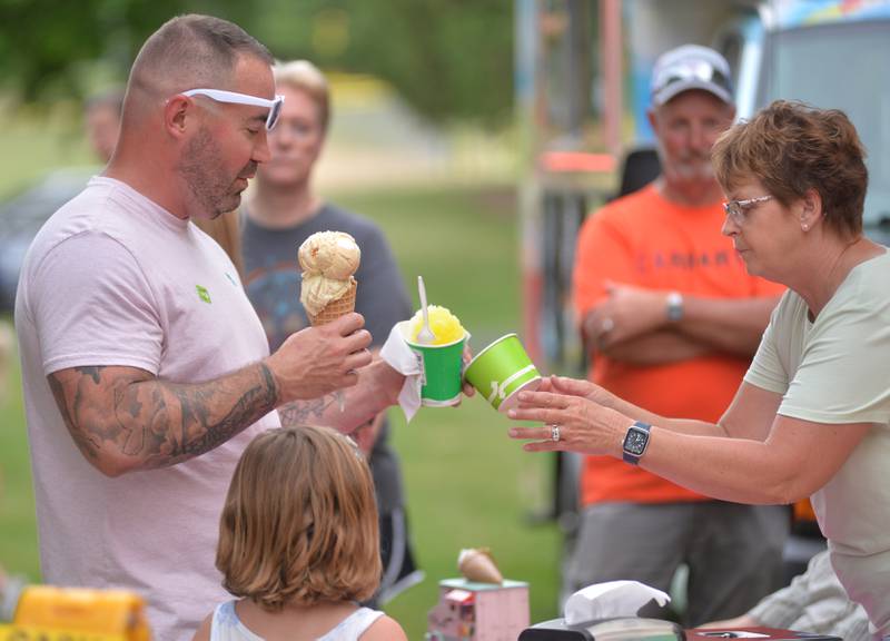 Matt Taylor of Chadwick juggles ice cream treats from Just 4 Fun during the Oregon Park District's Concert in the Park on Tuesday, June 17, 2025 at Oregon Park West. Matt and his daughter Ivy visited the popular ice cream truck on a hot and steamy night.