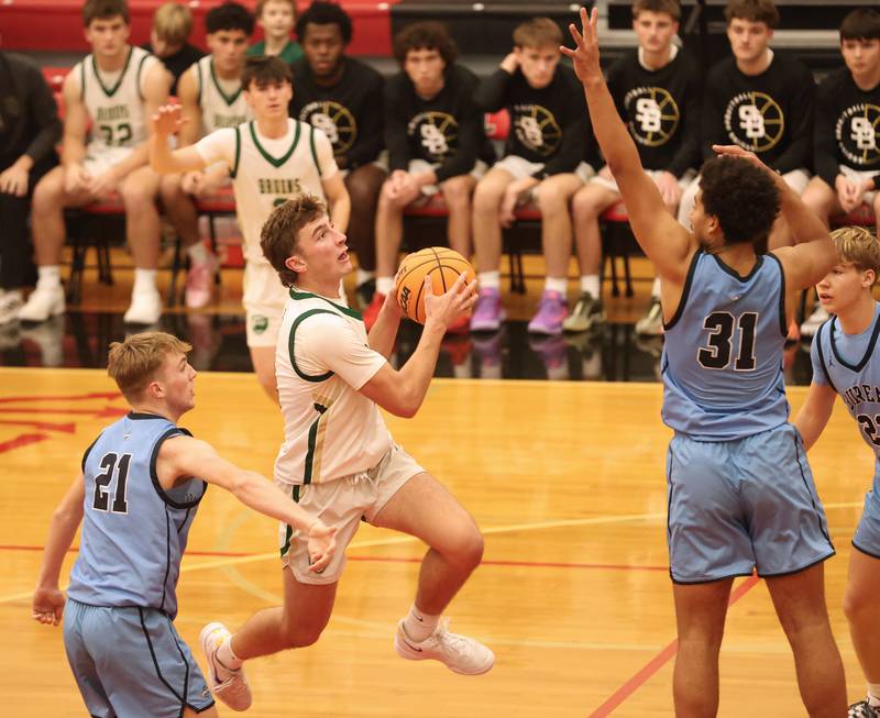 St. Bede's Gino Ferrari runs in the lane to score over Bureau Valley's Zac Wiggim and Dakarai Martin during the Colmone Classic on Thursday, Dec. 11, 2025 at Hall High School.