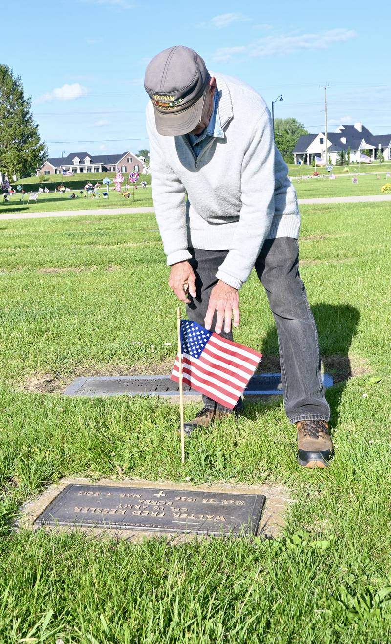 U.S. Air force veteran Phil Valle, who served in the Vietnam War, places a flag at a veteran's grave on Thursday, May 22, 2025, in Peru City Cemetery.