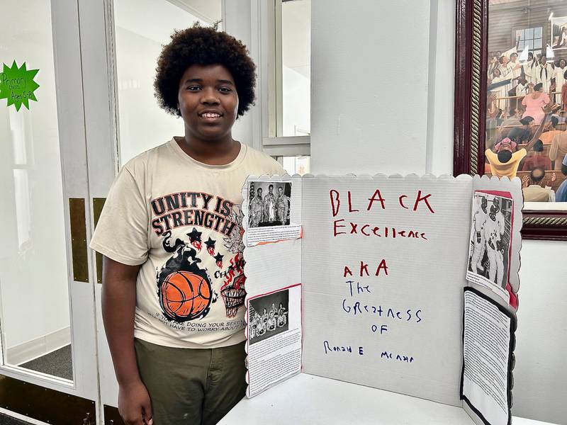 Diondre Stamps stands next to his poster board detailing the life of NASA astronaut and physicist Ronald E. McNair on Sunday, Feb. 16, 2025, at New Hope Missionary Baptist Church in DeKalb. The presentation was part of the church's annual Black History Month event "Displays of Excellence.”