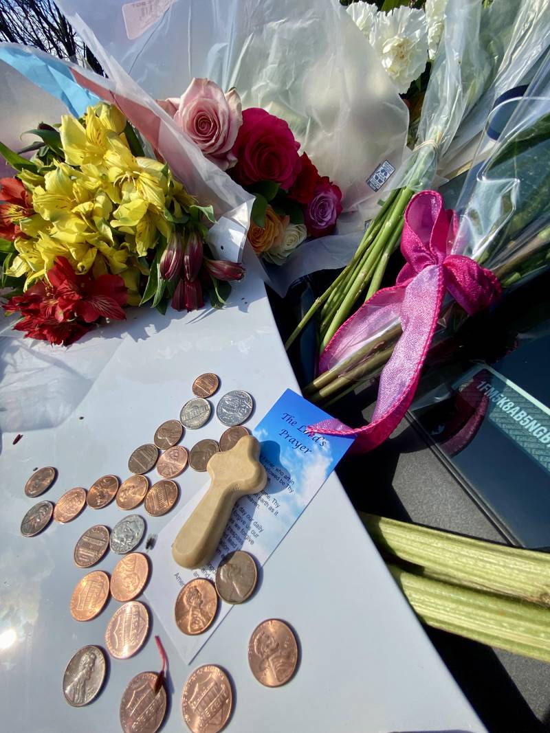 A prayer card lays on the hood of a DeKalb County Sheriff's Office vehicle displayed on the DeKalb County Courthouse lawn in Sycamore on Saturday, March 30, 2024. Mourners have visited the site to leave trinkets, flowers and other tokens in memory of sheriff's deputy Christina Musil, who was killed while on duty after her squad car was rear-ended by a truck Thursday, March 28, 2024.