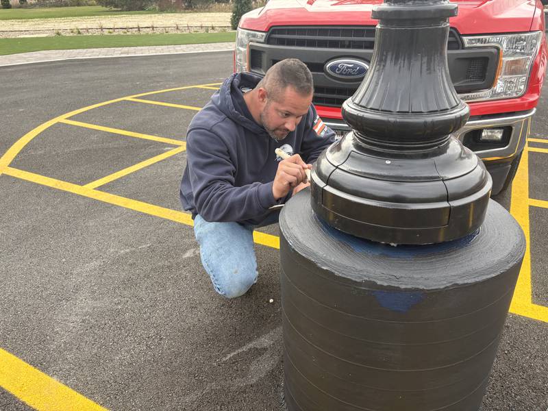Cesar Arellano paints a lightpost at the Shops on Main in Huntley Oct. 28, 2025.