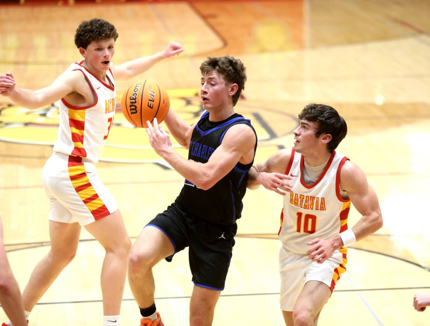 St. Charles North’s TJ Gleason tries to get the ball past Batavia’s Payton Wolf (left) and Joe Reid (right) during a game on Wednesday, Dec. 11, 2024 in Batavia.