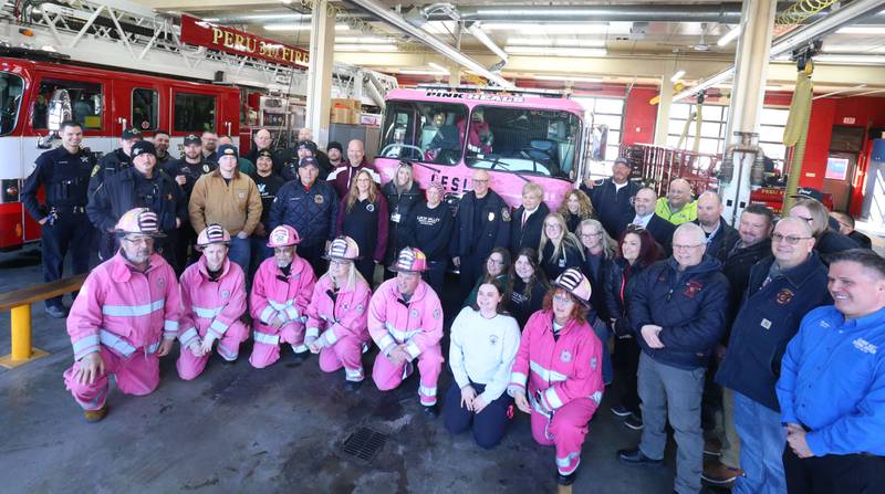 La Salle, Oglesby, Peru Fire and EMS personnel and local officials pose for a photo with Rachel Sienkiewicz next to the  Pink Heals firetruck on Thursday, Feb. 13, 2025 at the Peru Fire Station. Sienkiewicz is a telecommuicator at the Illinois Valley Regional Dispatch Center in Peru, who is battling uterine cancer. The Pink Heals Sauk Valley Chapter is a non profit providing communities with a program that supports people on a personal level in partnership with the public safety and local businesses.